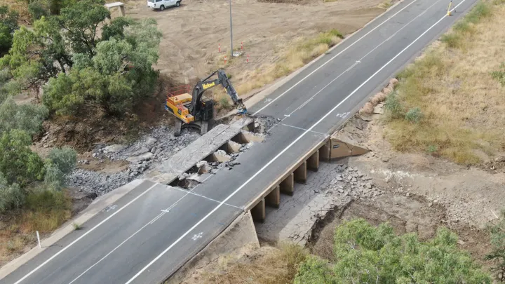 Excavator removing a bridge for a civil infrastructure project