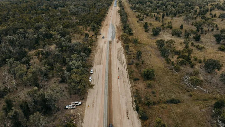 An expansive view of a regional road construction project in progress, surrounded by dense bushland, highlighting infrastructure development and civil engineering efforts in regional areas.