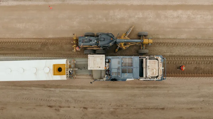 An aerial view of heavy machinery operating on a civil construction site, focusing on road preparation and infrastructure development for a regional project.