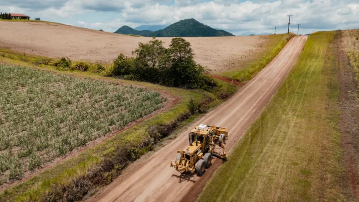 Yellow grader leveling a cassowary coast dirt road for a road stabilisation project