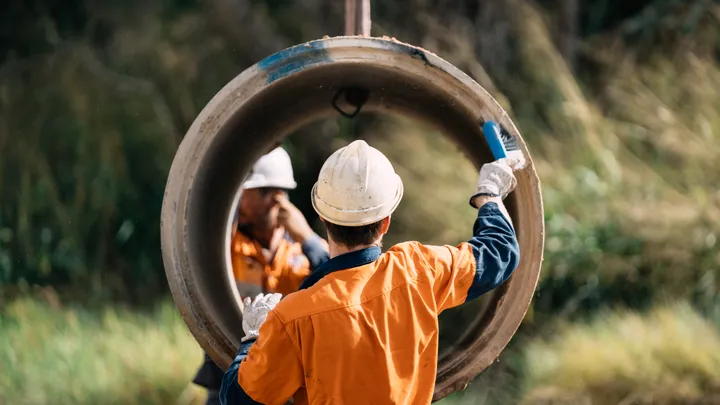 Construction workers adjusting concrete pipes