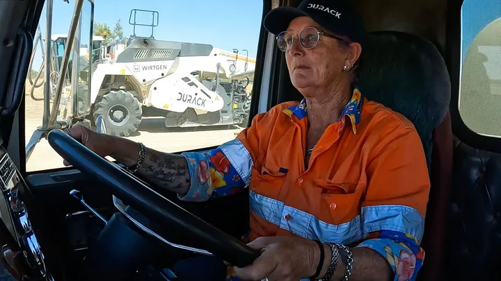 A Durack truck operator in a high-visibility uniform is focused at the wheel.